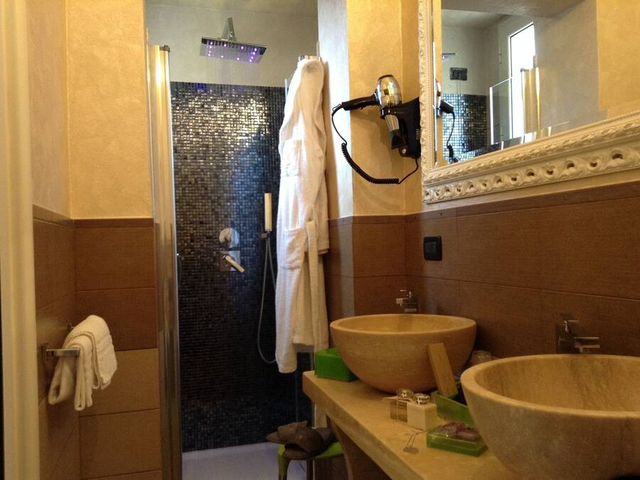 A bathroom with a shower, two sinks, a hairdryer, and a towel rack.