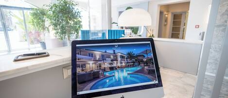 Um tablet mostra uma cena de hotel com piscina, luminária e planta.