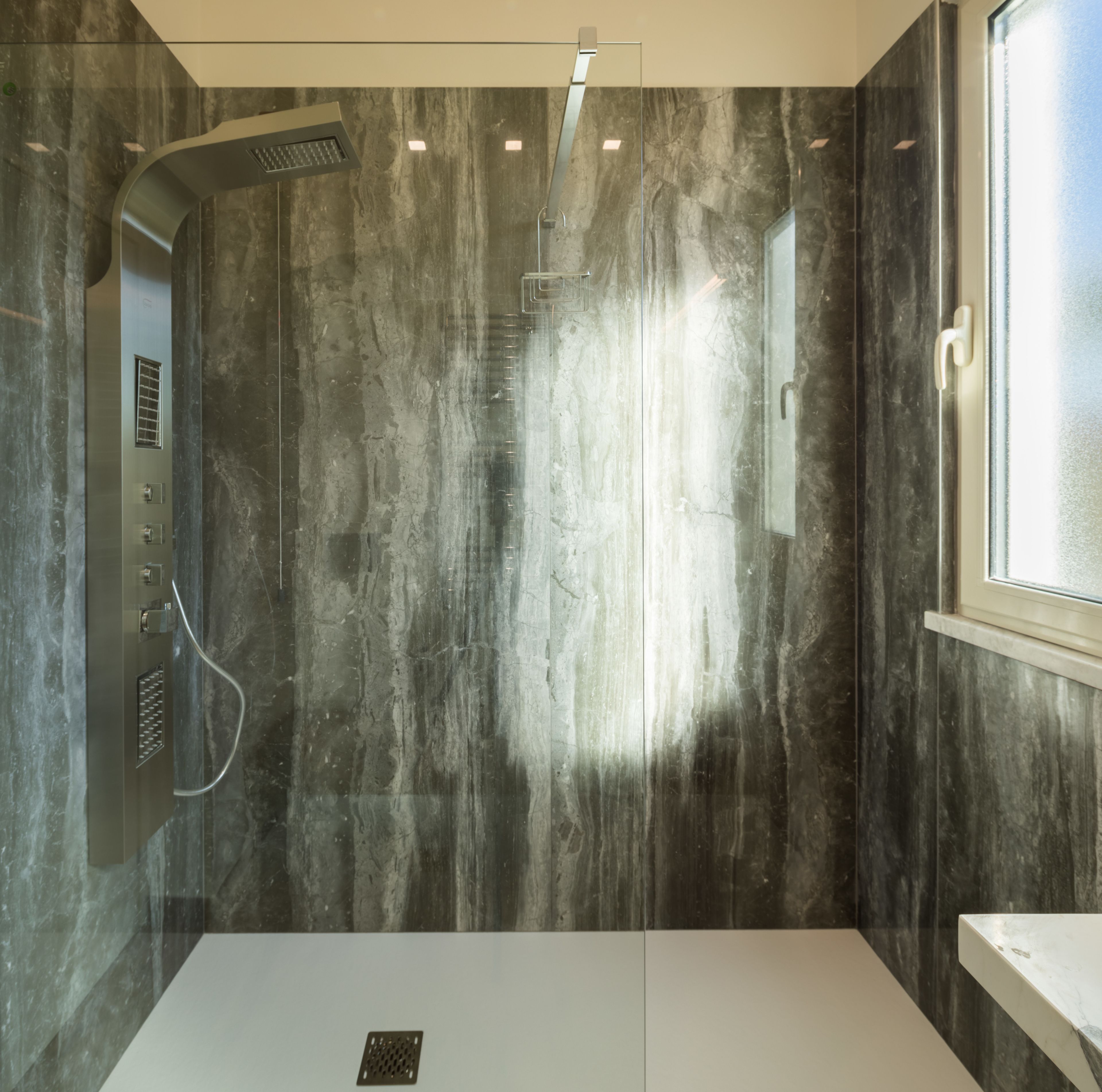 A modern bathroom with a shower, a window, and a sink.