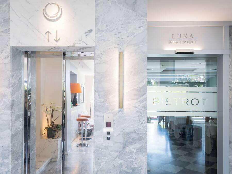 A hotel entrance with a marble wall, a glass door, and a sign for Luna Bistro.