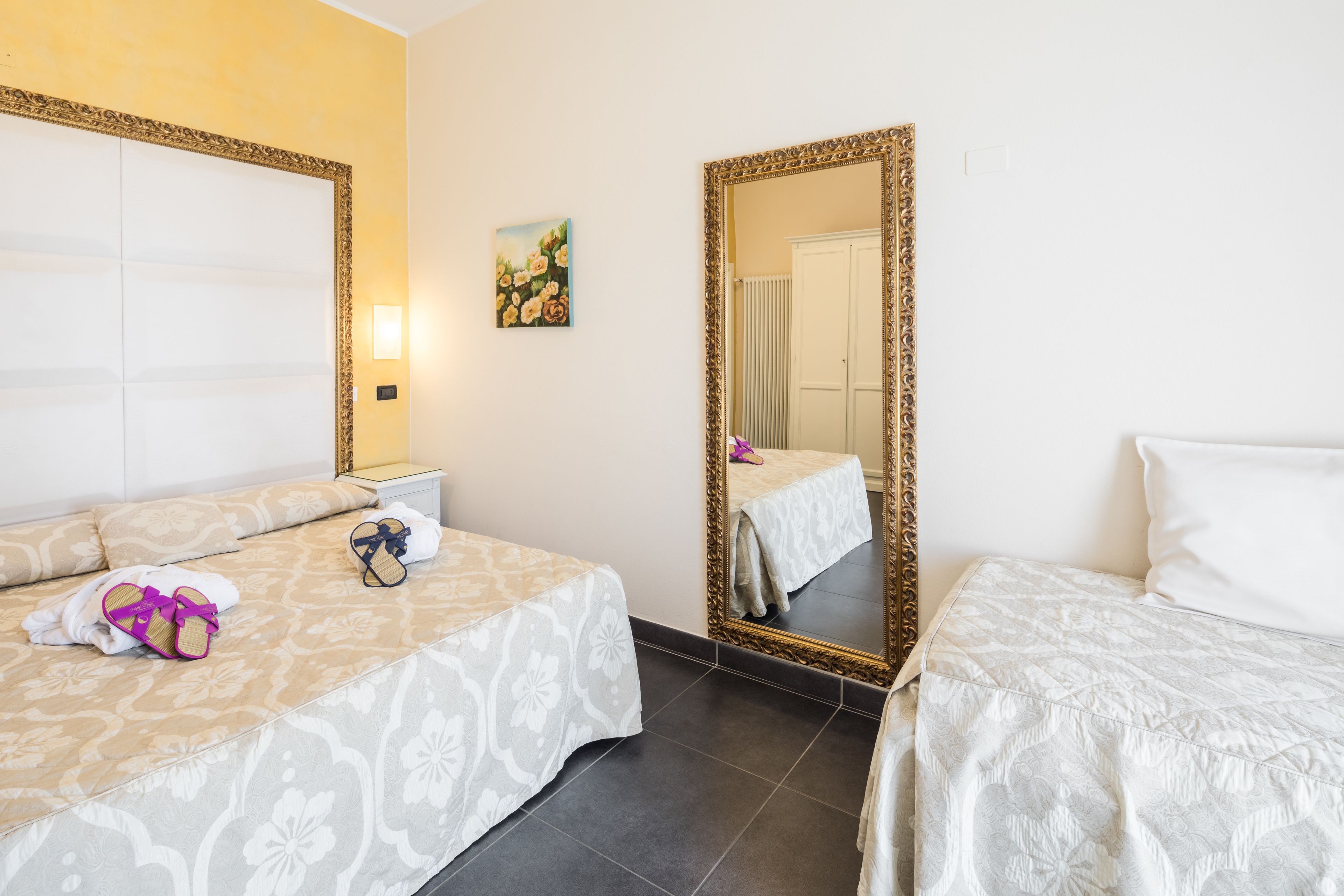 Ein Hotelzimmer mit zwei Betten, einem großen Spiegel und einem Bild an der Wand.