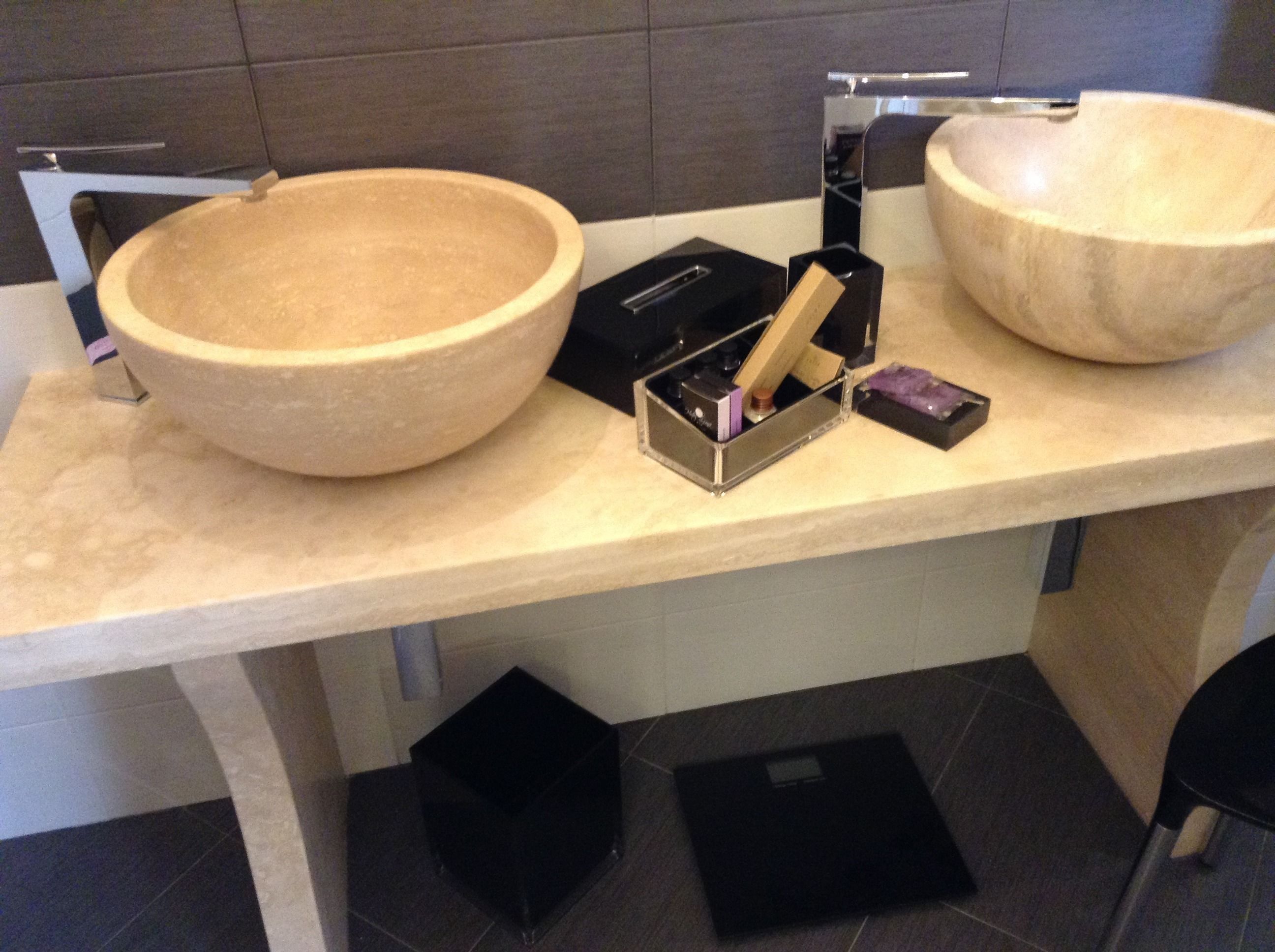 A bathroom with two large, round, beige sinks on a light-colored countertop.