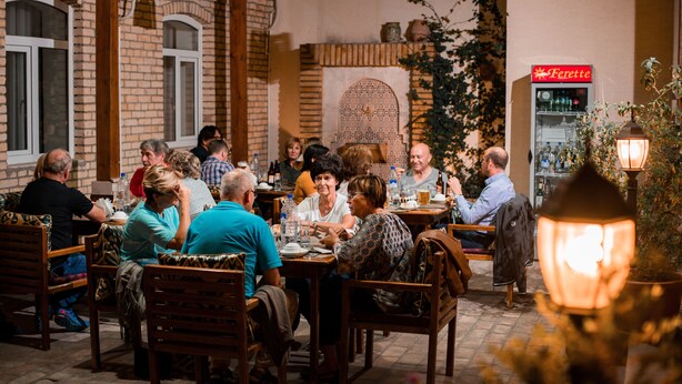 An outdoor dining area with brick walls, wooden furniture, and a brick fireplace.
