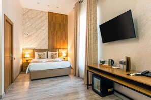 Une chambre d’hôtel équipée d’un lit, de lampes de chevet, d’une télévision, d’un bureau avec un téléphone et d’une machine à café.