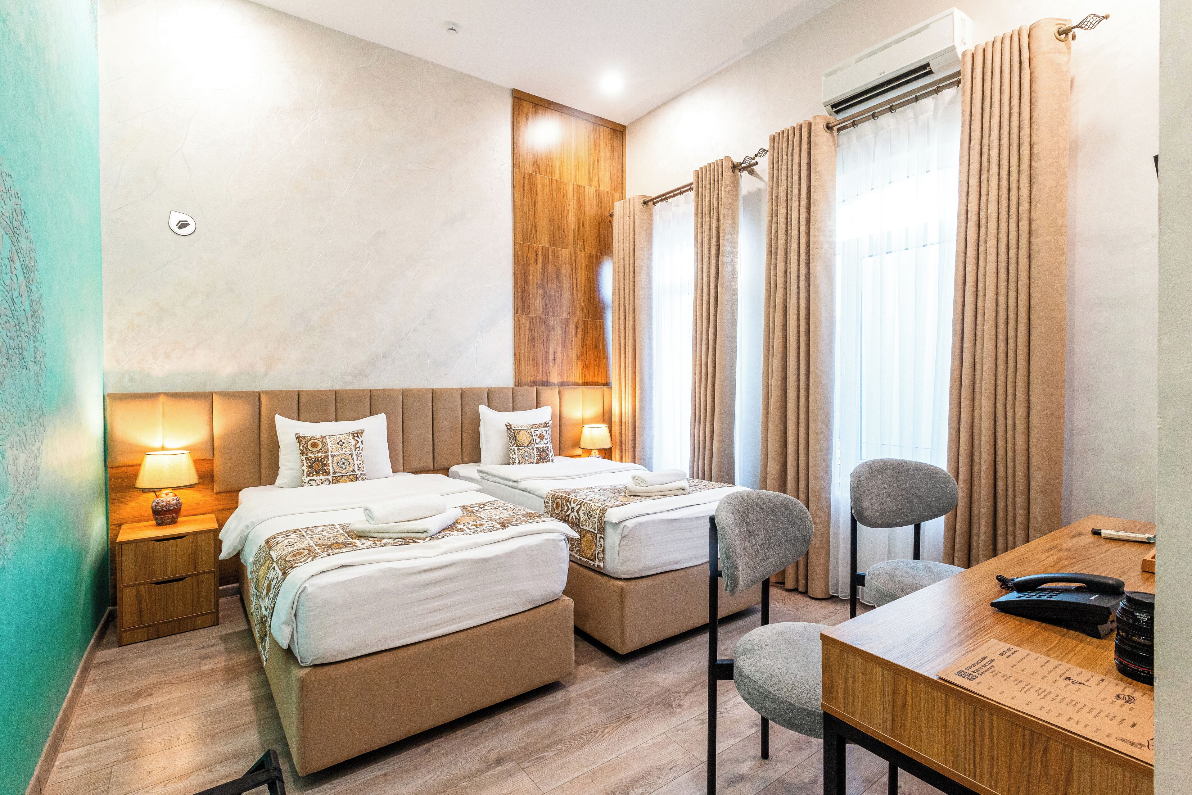 Habitación de hotel con dos camas, un escritorio, una silla y un aire acondicionado.