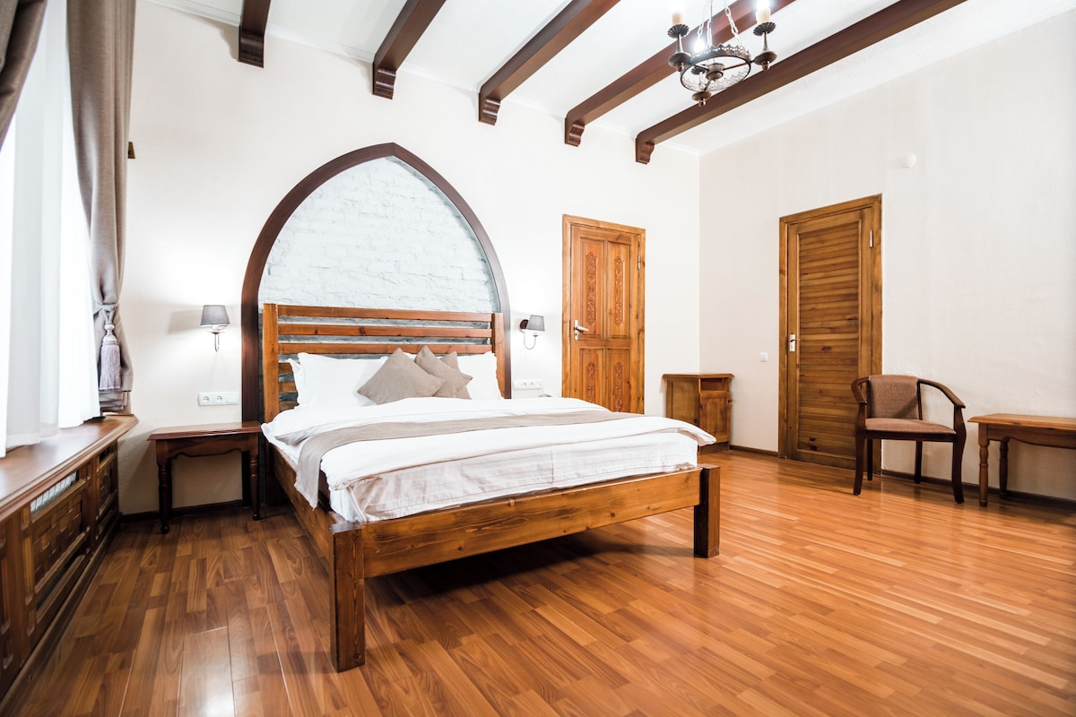 Un dormitorio con cama de madera, mesita de noche, una silla y un armario de madera.
