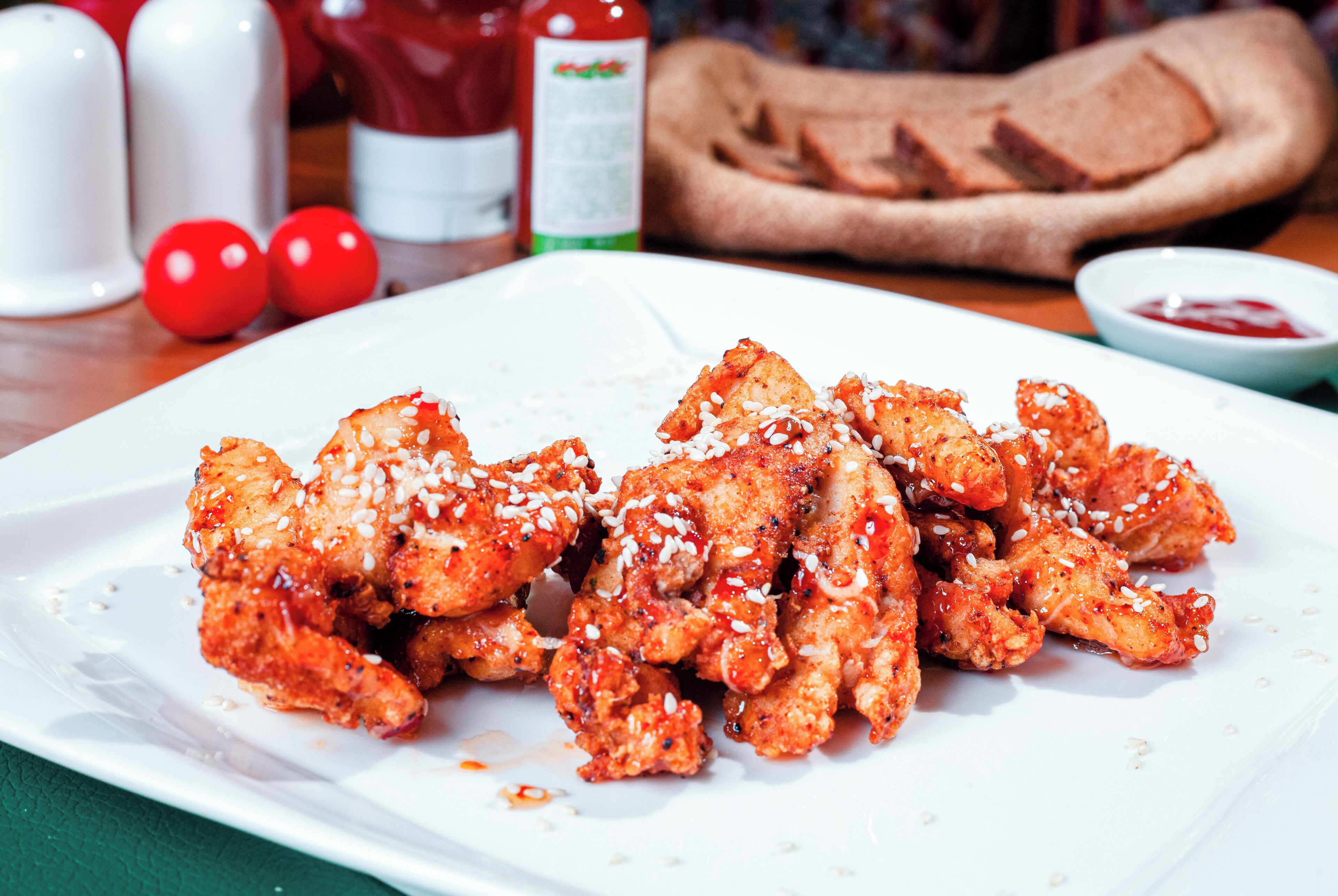 Un plato de pollo con semillas de sésamo y una guarnición de kétchup.