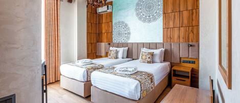 A hotel room with two beds, a wooden headboard, a wall mural, and a small wooden table.