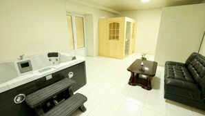 A modern bathroom with a bathtub, vanity, and bench. There is a wooden cabinet with glass doors and a small table with a vase.