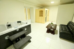 Une salle de bain moderne avec une baignoire, un meuble-lavabo et un banc. On y trouve un meuble en bois avec des portes en verre et une petite table sur laquelle est posé un vase.