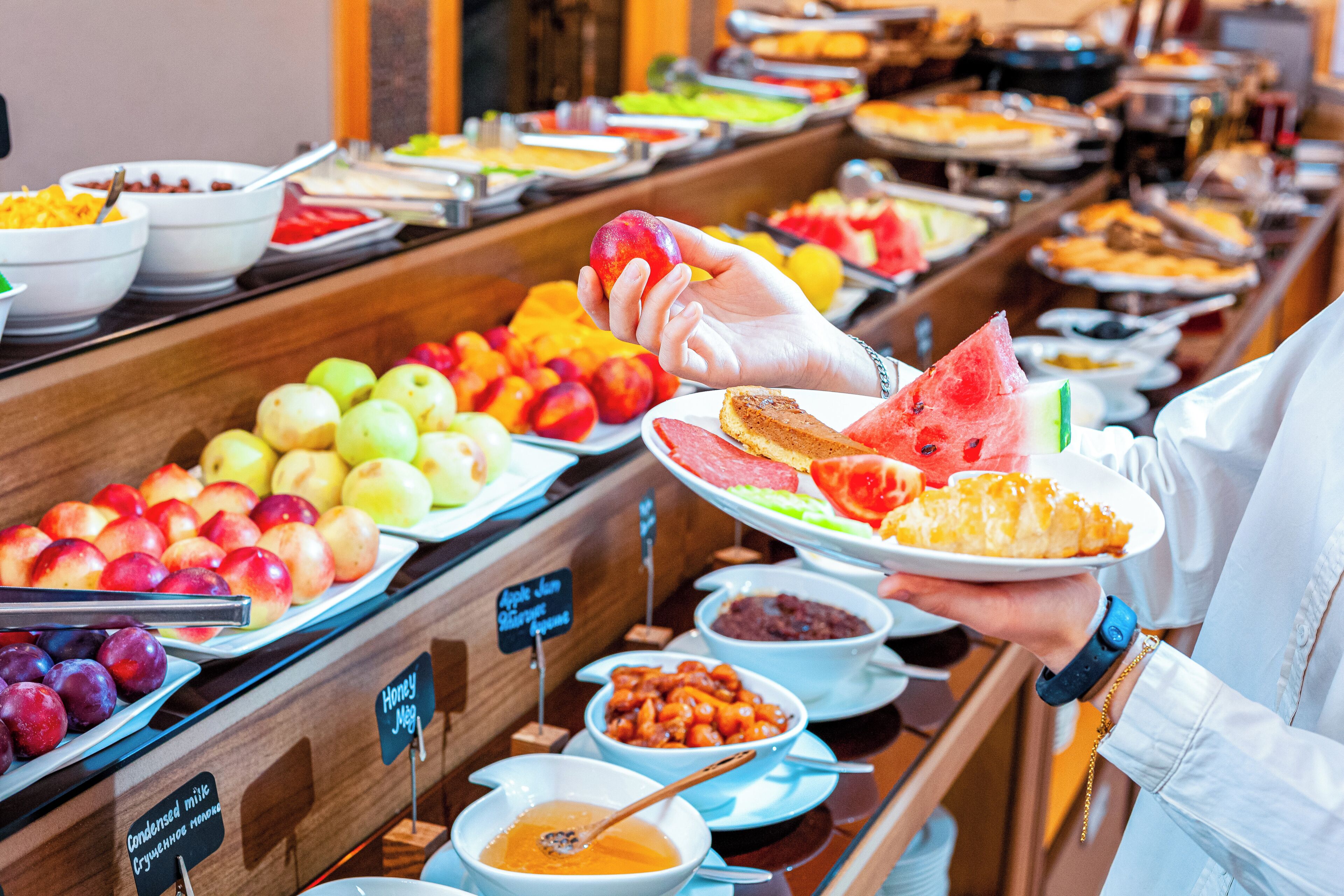 A buffet with various food items including fruits, vegetables, and condiments.