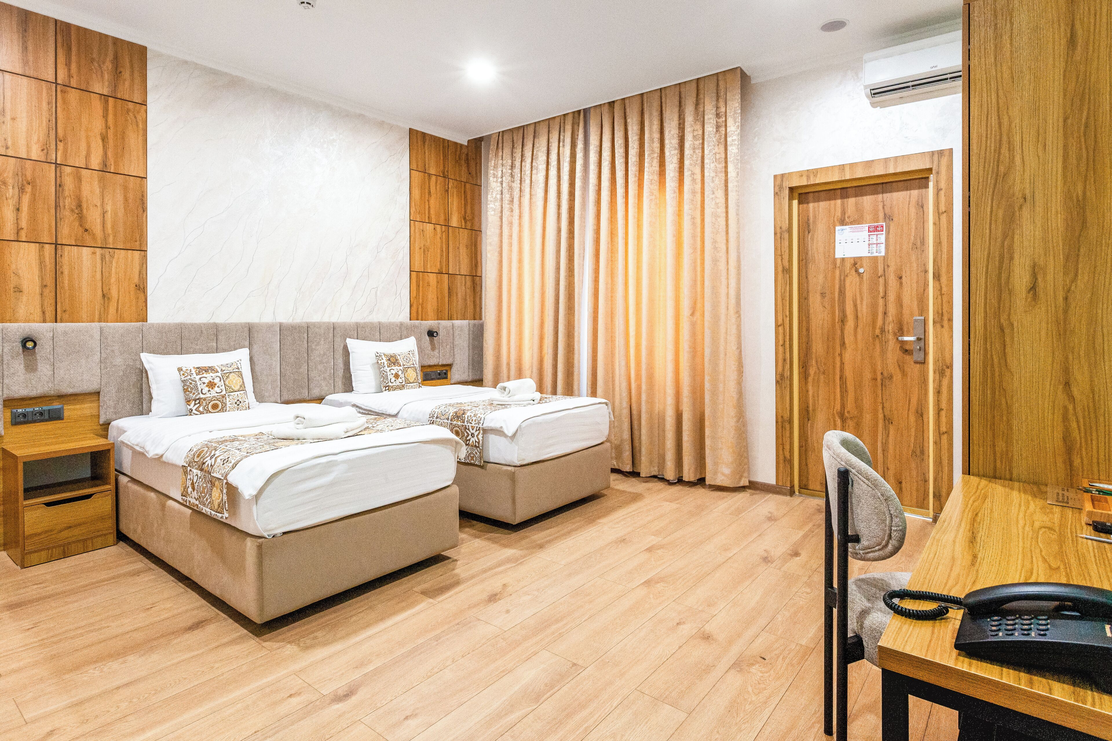 Habitación de hotel con dos camas, un escritorio con teléfono y una silla.