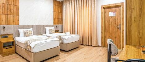 Habitación de hotel con dos camas, un escritorio con teléfono y una silla.