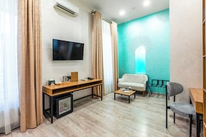 Een moderne woonkamer met een flatscreen televisie, een houten bureau, een bank en een salontafel.