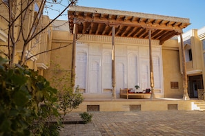 Un patio con una zona de estar techada, un muro decorativo con diseños intrincados y un suelo de ladrillo.