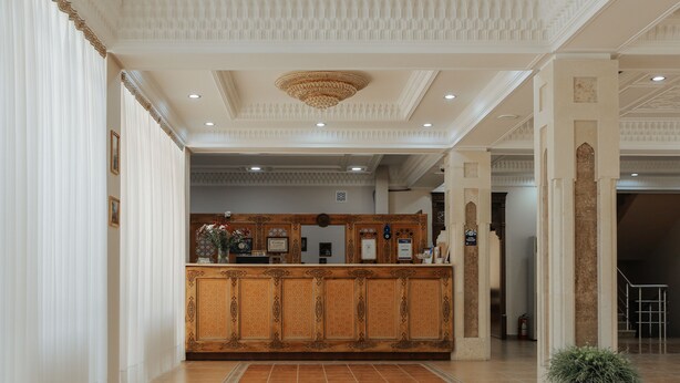 Un área de recepción con un mostrador de madera, techo decorativo y piso de baldosas.