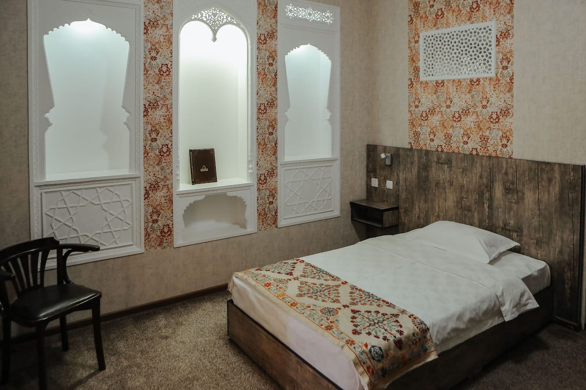 A bedroom with a bed, a chair, and decorative windows.
