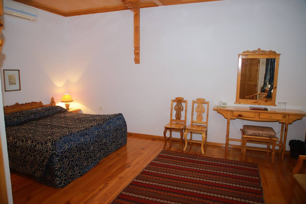 Une chambre à coucher comprenant un lit, un bureau, deux chaises, un miroir et une lampe.