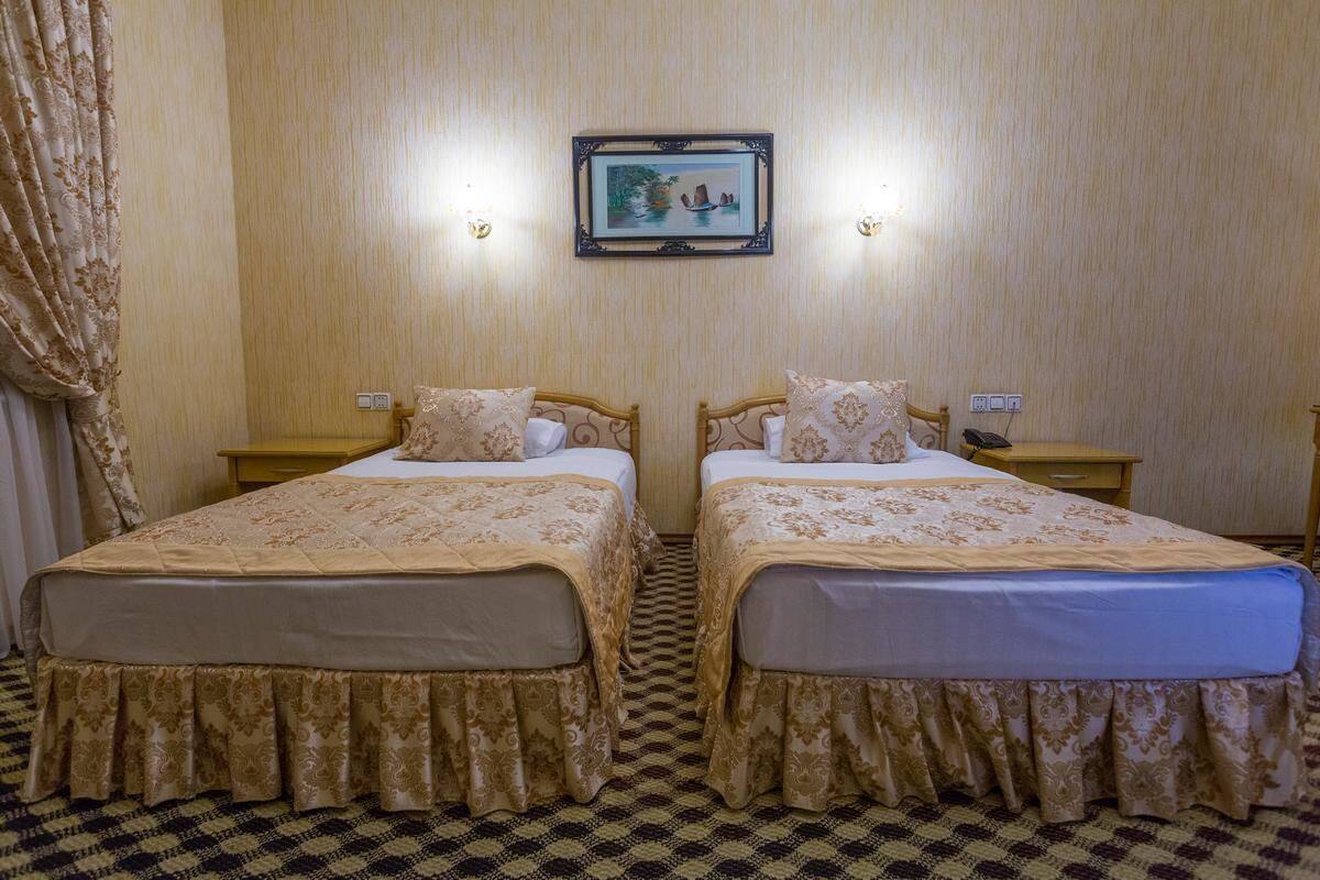 Habitació d'hotel amb dos llits, un terra de quadres, un quadre al mur i dues làmpades de nit.