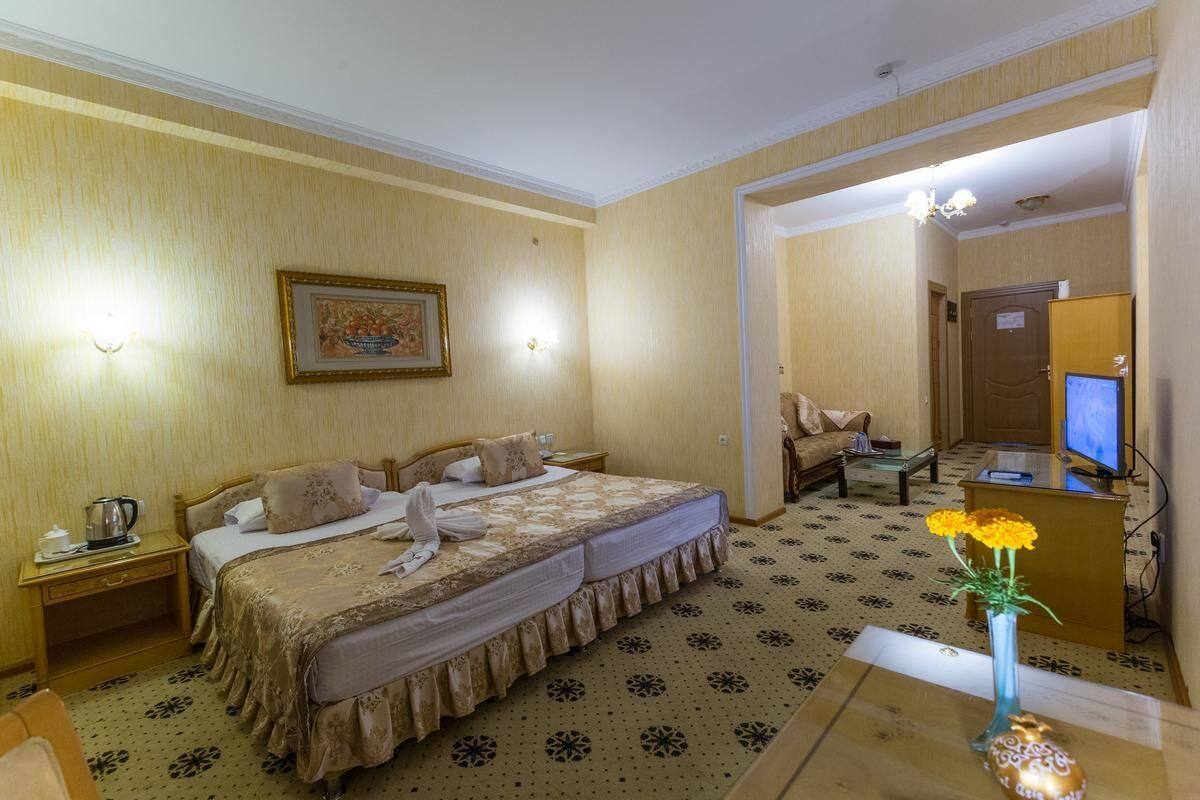 Habitació d'hotel amb un llit gran, un escriptori amb ordinador, televisió i un ram de flors.