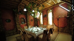 A dining area with a brick wall, arched windows, and hanging plants. - Asia Bukhara Hotel (Bukhara)