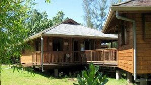 A wooden cabin with a porch, surrounded by greenery. - Vaianae Lodge (Moorea-Maiao)