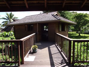 A wooden house with a covered porch and a small garden. - Vaianae Lodge (Moorea-Maiao)