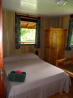 A room with a bed, a wooden wardrobe, and a window with curtains. - Vaianae Lodge (Moorea-Maiao)