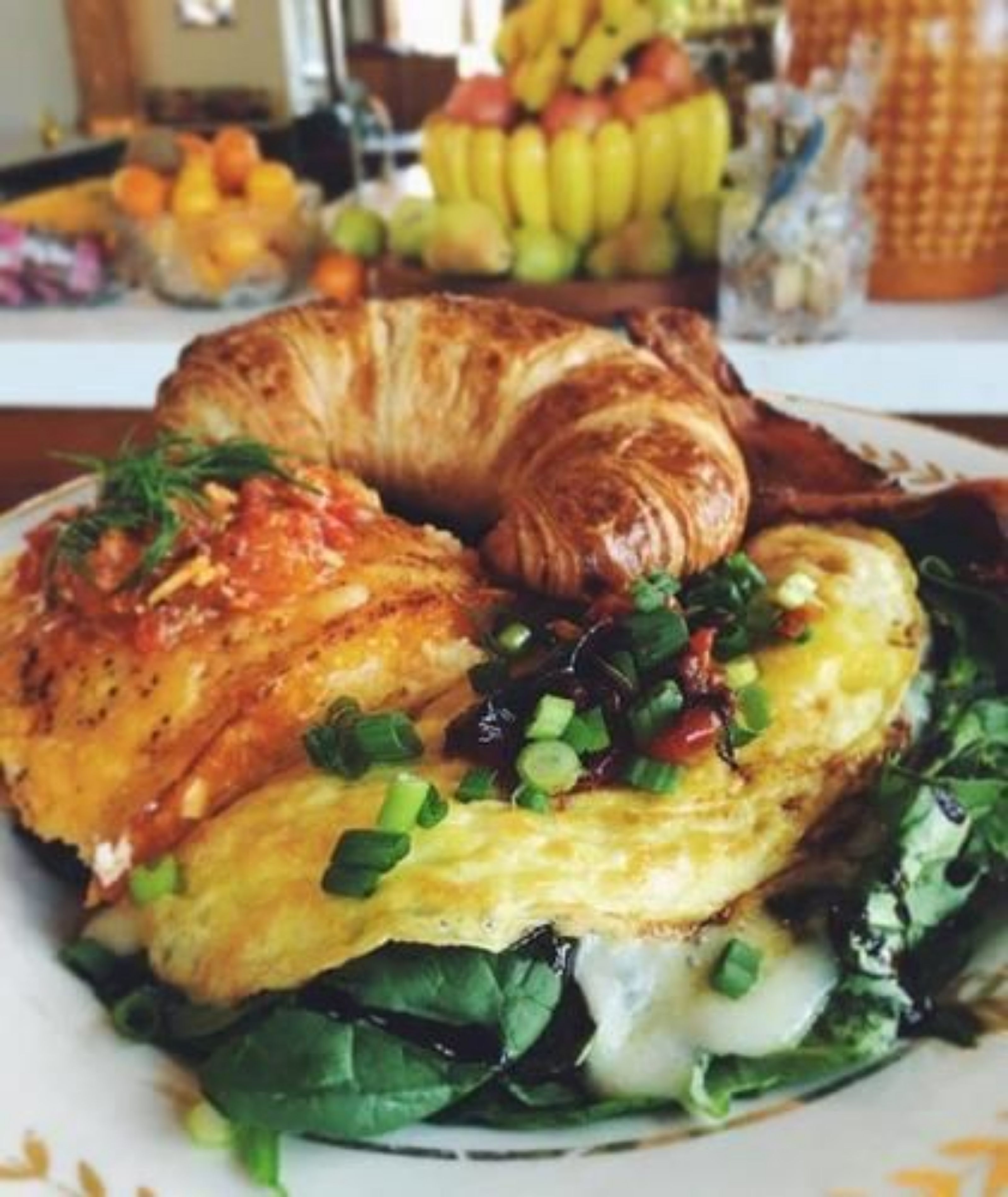 Un plat amb croissant, ous remenats i espinacs.