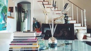 A staircase with a white railing, a chandelier, and a fireplace. - Black Dolphin Inn (New Smyrna Beach)