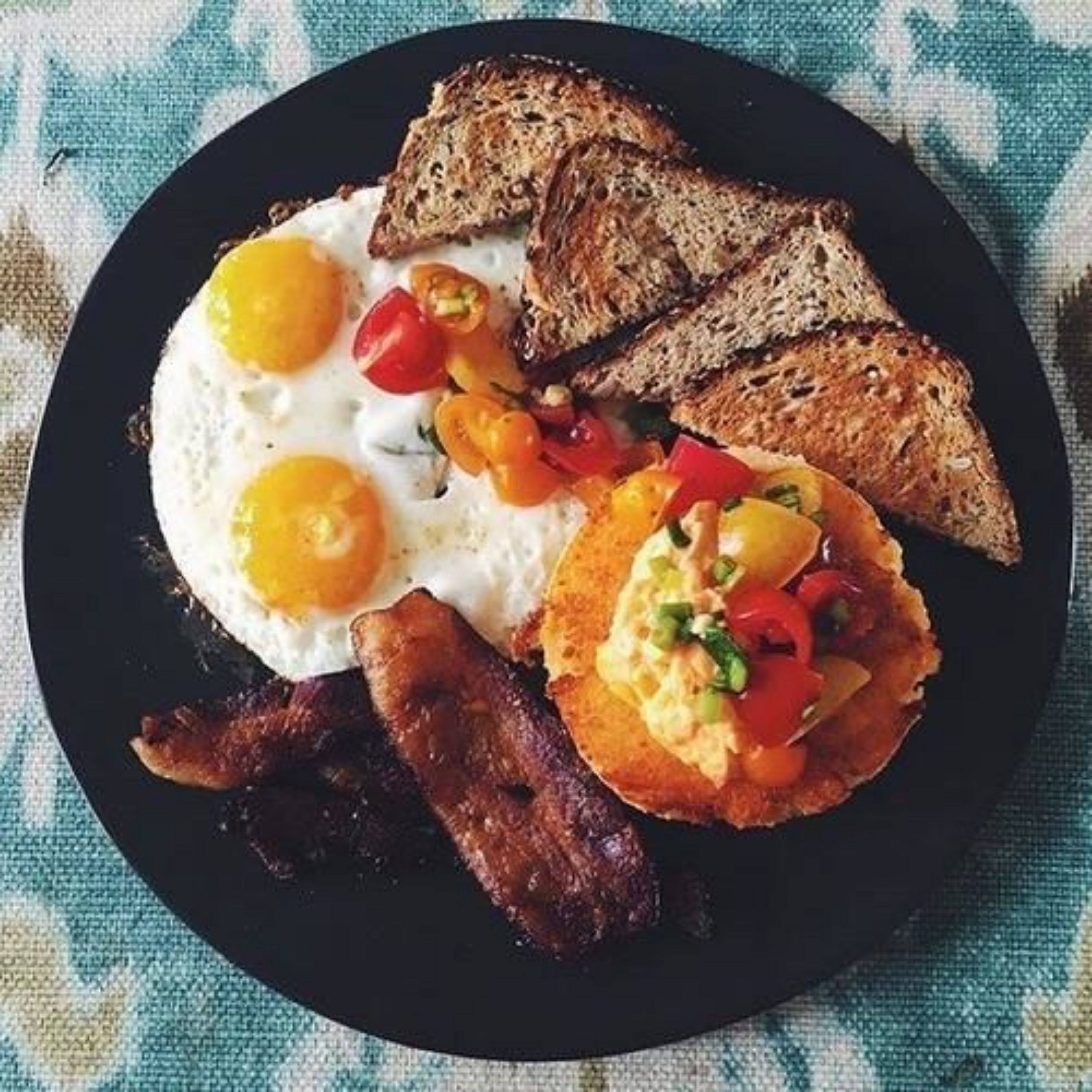 A breakfast plate with eggs, bacon, toast, and a fried egg on toast.
