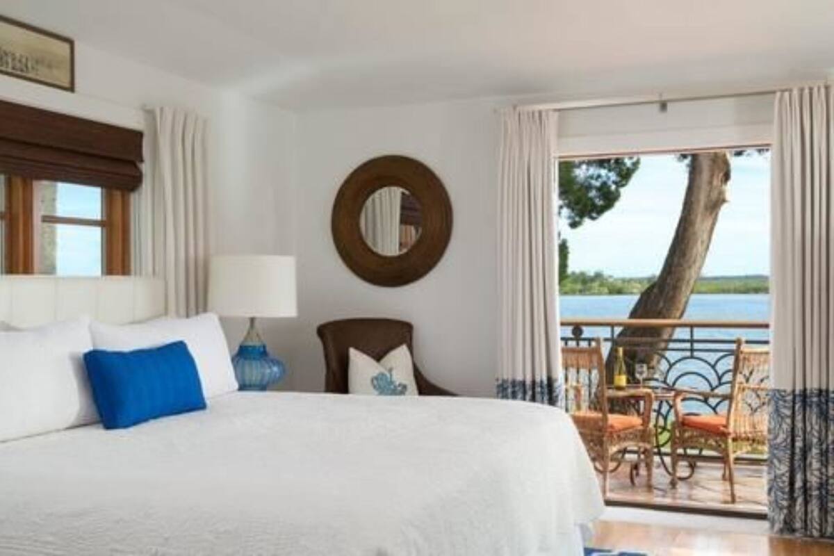 Una camera d'albergo con un letto, una sedia, un tavolo e vista su un corpo d'acqua.