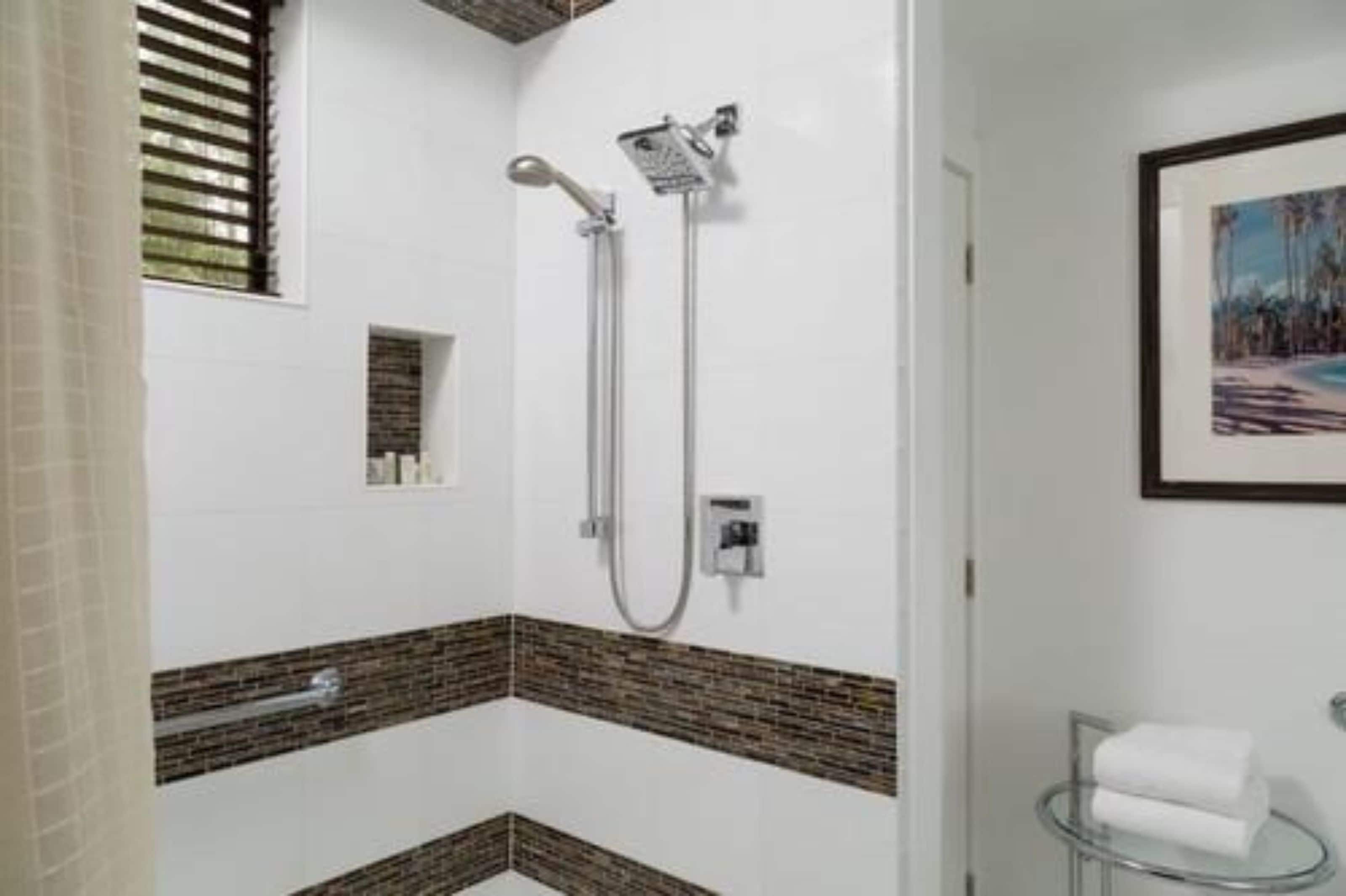 Un baño moderno con ducha, tocador con tapa de cristal y un cuadro enmarcado en la pared.