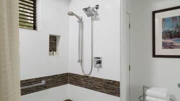 A modern bathroom with a shower, a glass-topped vanity, and a framed picture on the wall.