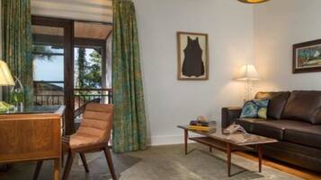 A living room with a brown leather sofa, a wooden coffee table, a brown leather chair, a glass table, and a window with green curtains.