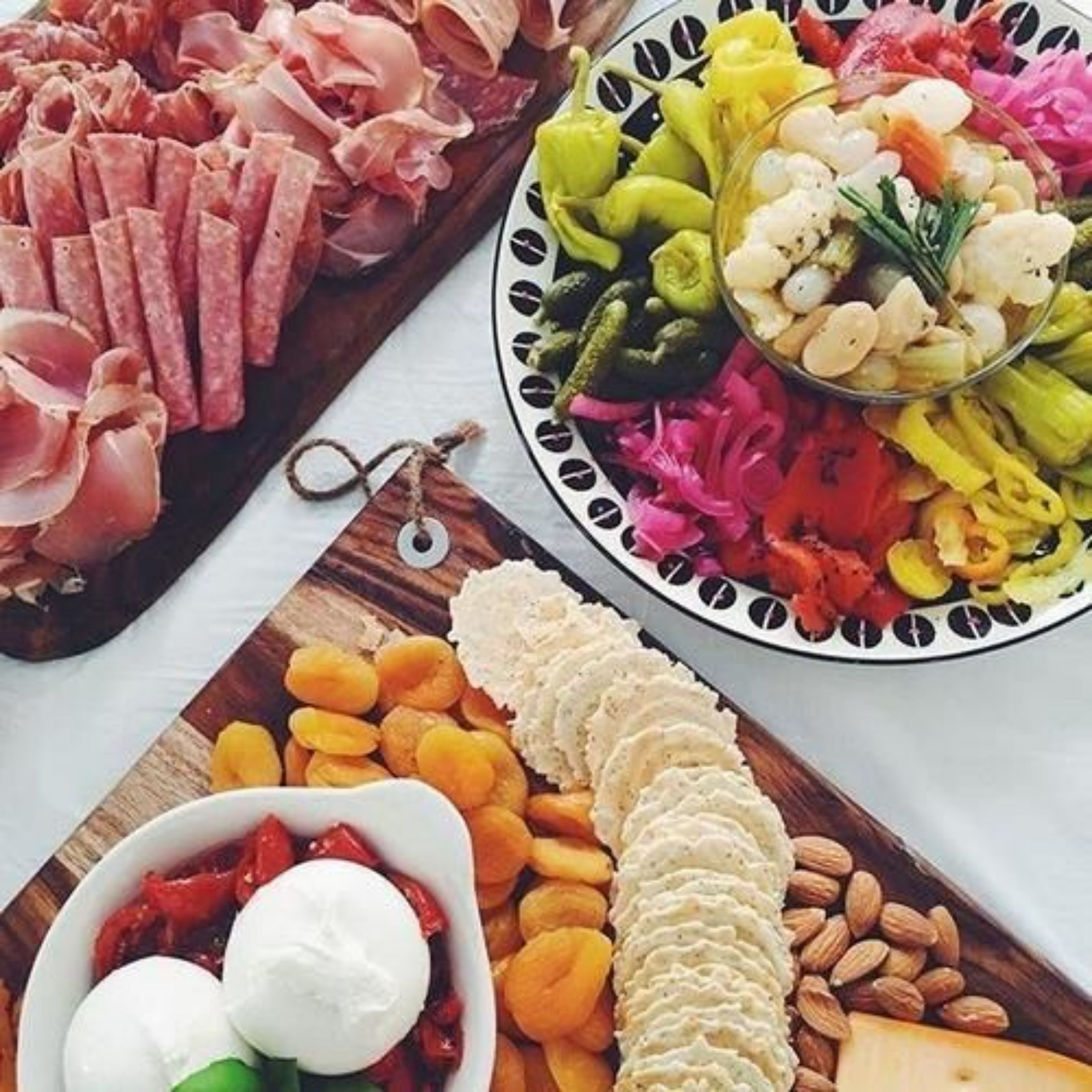 A charcuterie board with various meats, cheeses, and fruits.