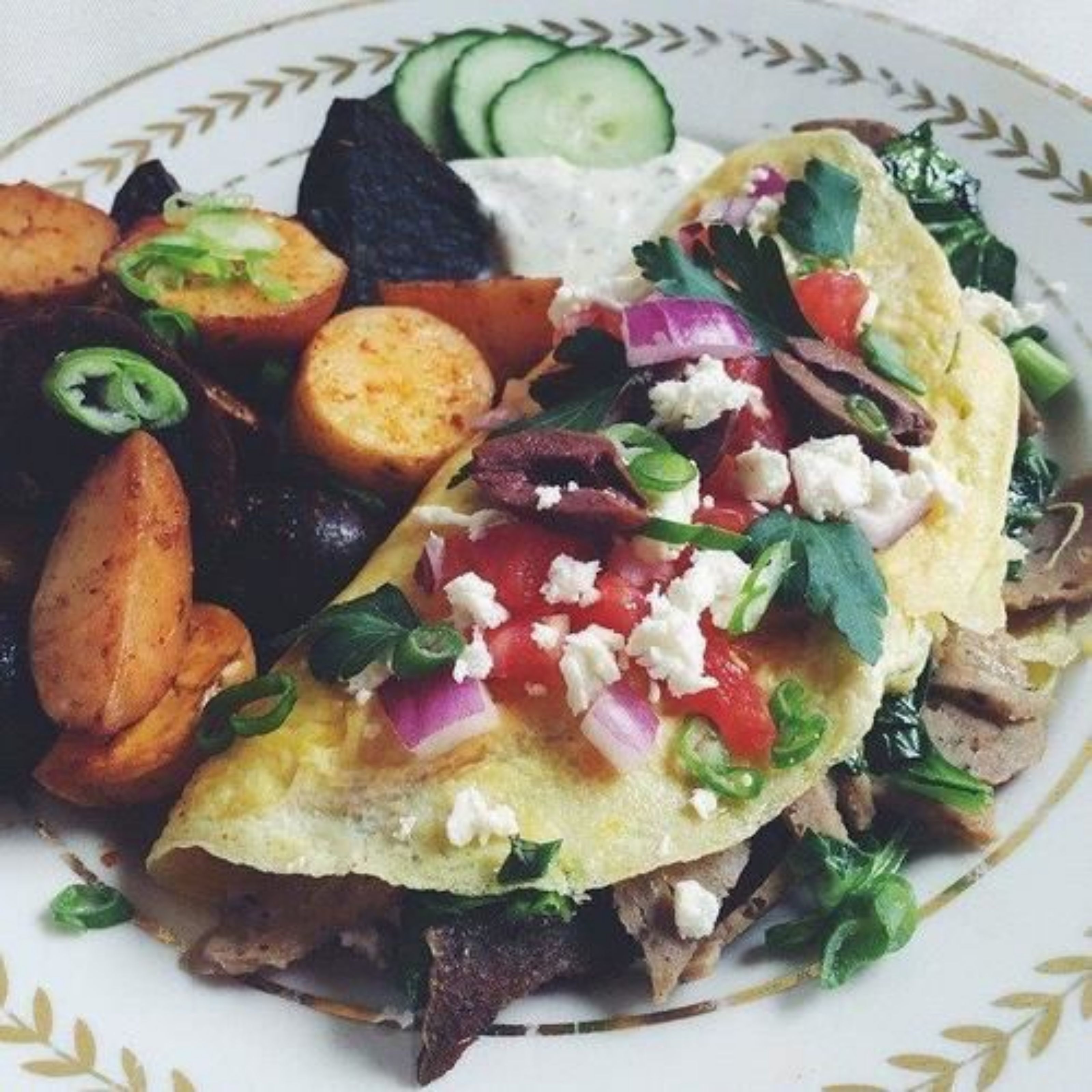 A plate with a taco, sliced potatoes, a slice of avocado, and a dollop of sour cream.