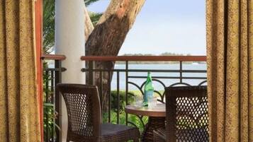 A balcony with wicker chairs and a table, overlooking a body of water.