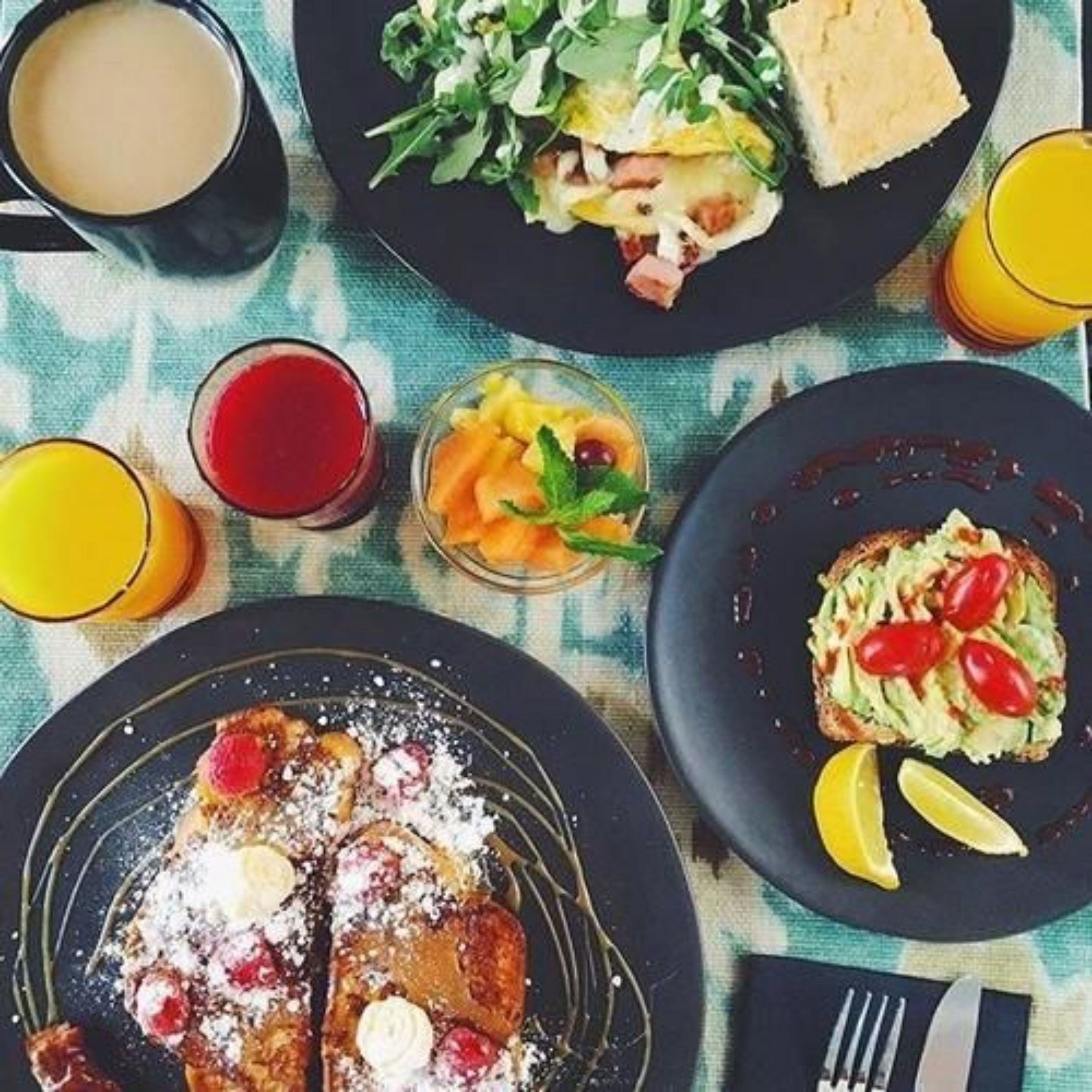 A breakfast setting with plates of food, a cup of coffee, and glasses of orange juice.