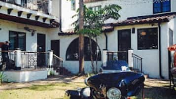 A two-story building with a balcony, a motorcycle parked in front, and a clear sky.