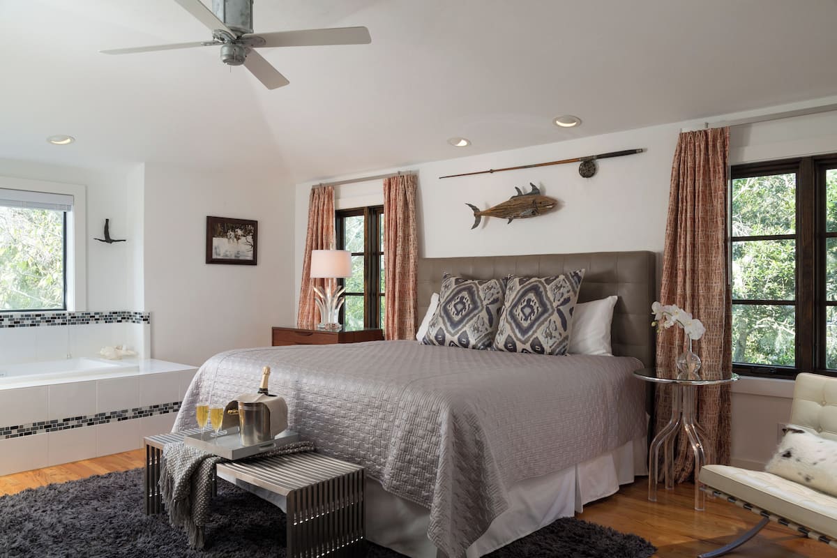 Una camera da letto con un letto grande, un comodino con una lampada, una finestra con tende e una decorazione a forma di pesce sul muro.