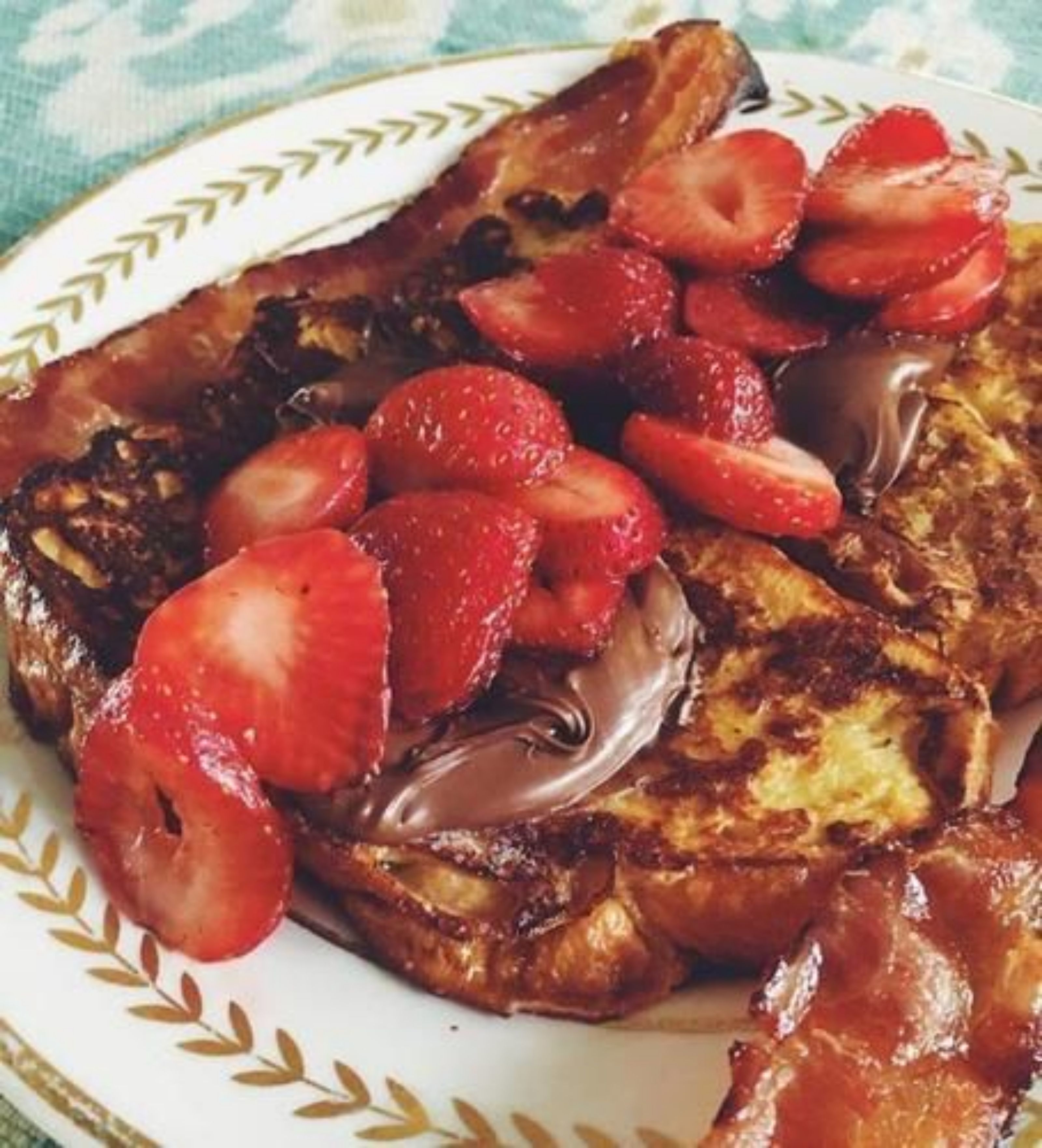 Un plato de tostadas francesas cubiertas de fresas y salsa de chocolate.