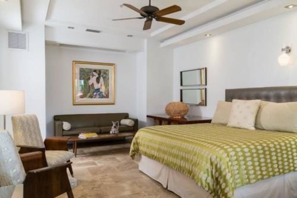 Una camera da letto con un letto, una ventola a soffitto, un divano, un tavolino da caffè e un quadro appeso al muro.
