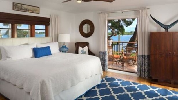 A bedroom with a bed, a ceiling fan, a window, and a view of the outdoors. - Black Dolphin Inn (New Smyrna Beach)