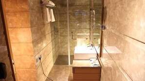 A bathroom with a glass shower enclosure, a sink, and a towel rack. - Middleton Inn (Kolkata)