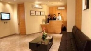 A hotel lobby with a reception desk, a black sofa, and a coffee table. - Middleton Inn (Kolkata)