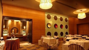 A conference room with multiple tables, a large mirror, and decorative wall sconces. - Middleton Inn (Kolkata)