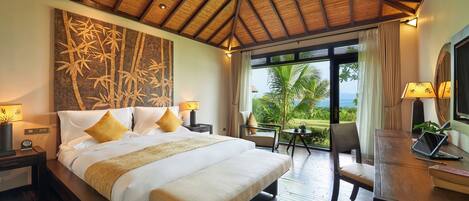 A bedroom with a bed, bedside tables, a desk, a chair, a ceiling fan, and a view of the outdoors.
