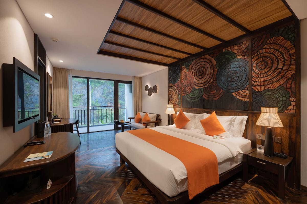 Une chambre d’hôtel avec un grand lit, un bureau, une télévision et un balcon avec vue.