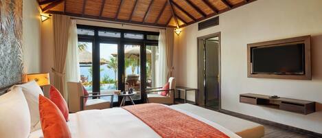 Habitación de hotel con cama, televisión, escritorio con silla y vista al océano.